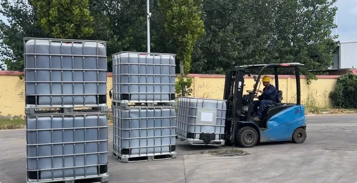 Forklift placing DOTP IBC totes on empty ground at warehouse yard, preparing for truck loading