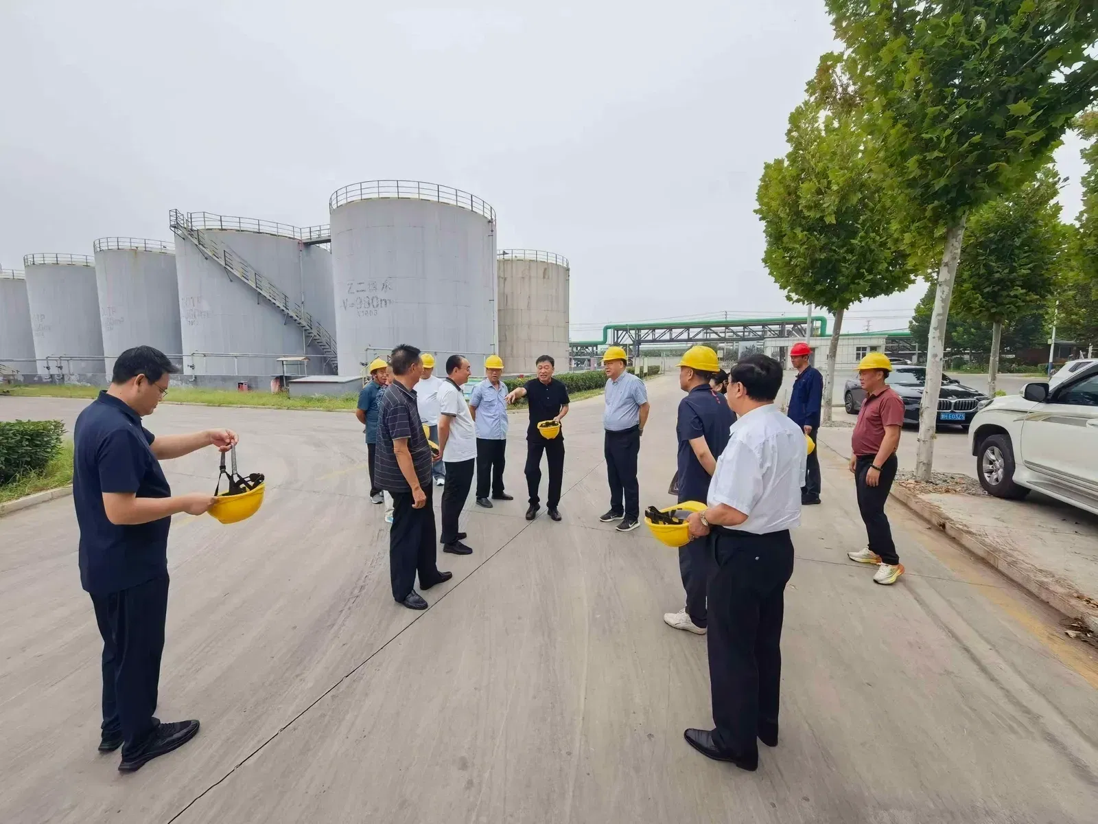 到访万生 DOTP 厂区的中国 PVC 膜与人造革客户与我司员工在西门入口佩戴安全帽准备进入审核
