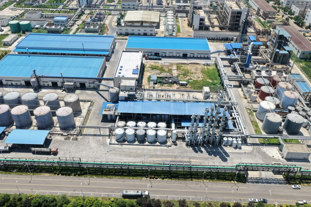 Aerial overview of Wansheng DOTP factory showing raw-material yard, distillation towers, tank farm and biomass gasifier