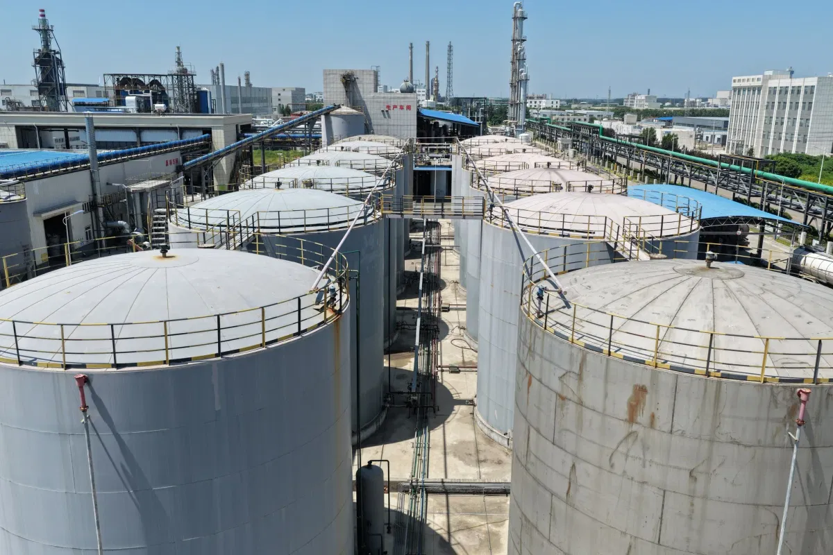 Finished-product storage tank farm at Wansheng DOTP factory with production workshop visible in the background
