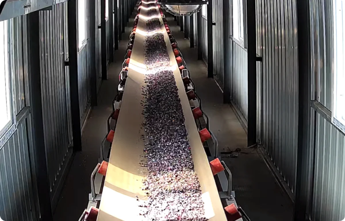 Automated conveyor belt feeding shredded PET flakes into the Jining Wansheng recycled-PET plasticizer production line for DOTP manufacturing